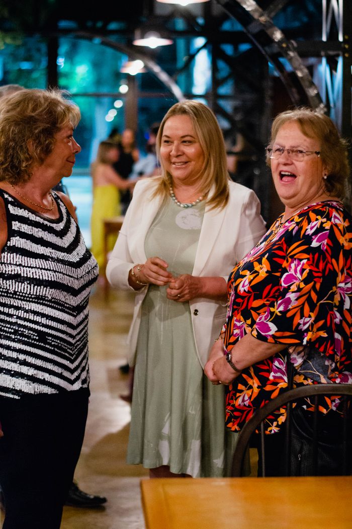 Smiling women engaged in lively conversation at an indoor event, capturing genuine enjoyment.